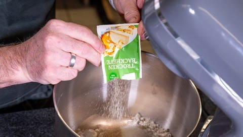 Trockenhefe wird in die Rührschüssel zum Mehl geschüttet: Um den Kassler im Brotteig im Backofen zuzubereiten, braucht es nach dem Rezept von SWR4 Konditor Joachim Habiger einen Hefeteig. (Foto: SWR, Corinna Holzer)