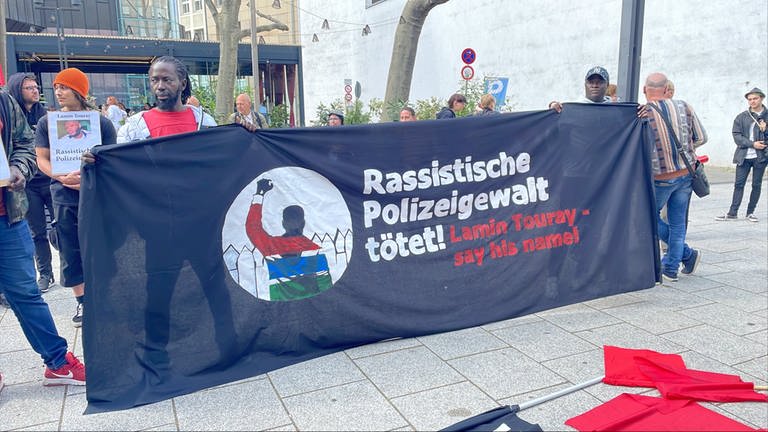 Mit einem großen Banner demonstrieren Menschen in Stuttgart gegen Polizeigewalt. Auslöser war der Tod des Gambiers Lamin Touray.  (Foto: SWR, Sissy Hertneck)